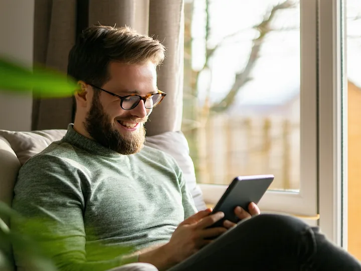Person reading a care plan document on a tablet with a peaceful, relieved expression, sitting by a window